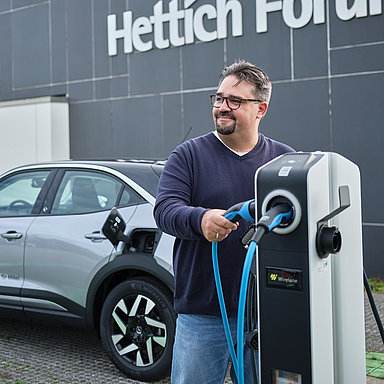 Person an einer Ladestation für Elektroautos vor dem Hettich Forum